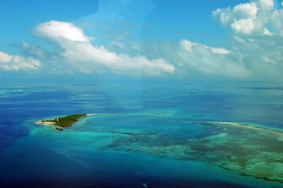 An aerial view of Chumbe Island, a small wooded island ringed by pale reef in the deep blue Indian Ocean
