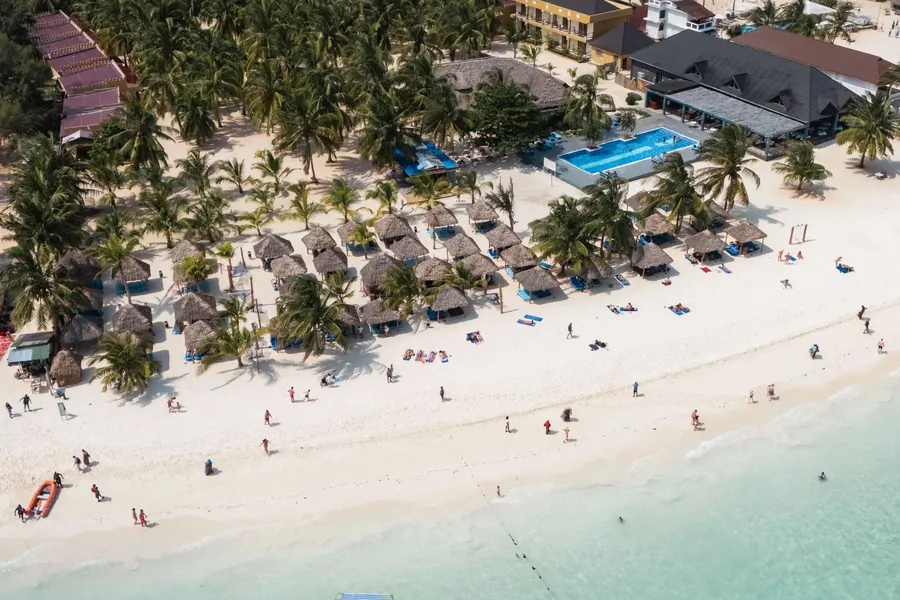 Looking down on the wide white beach at Kendwa, swimmers in the clear shallows and parasols under the palms