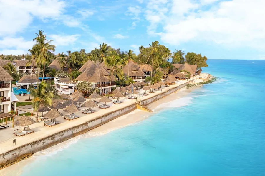 Thatched beach hotels along the shore at Nungwi on the northern tip of Zanzibar, turquoise water lapping the sand below them